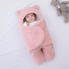 Bébé paisible allongé sur un lit, enveloppé dans un nid d'ange rose, à côté d'une peluche ourson, illustrant le confort et la douceur que ces accessoires pour bébé apportent.