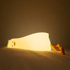une veilleuse canard illuminée sur un lit créant une ambiance relaxante.