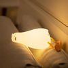 Une veilleuse canard illuminée sur deux coussins dans une chambre d'enfant.