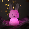 Veilleuse en forme de lapin illuminée en violet dans une ambiance féerique.