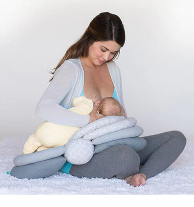 Une jeune maman allaitant son bébé avec le coussin d'allaitement réglable multi positions. Le coussin d'allaitement offre un soutien pour le bébé, ce qui permet une position confortable pour la maman et le bébé pendant l'allaitement.