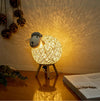 Veilleuse mouton tissée à la main, nommée SHEEPY, posée sur une table, émettant une lumière tamisée et douce grâce à son variateur d'intensité.