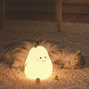 Veilleuse LED en forme de poire diffuse une lumière douce, illuminant doucement la pièce à côté d'un chat qui dort. Crée une ambiance relaxante et respectueuse du sommeil.